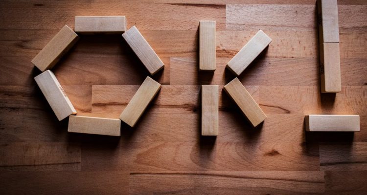 Wooden blocks arranged to spell 'OK' on a wooden tabletop, showcasing creativity in design.